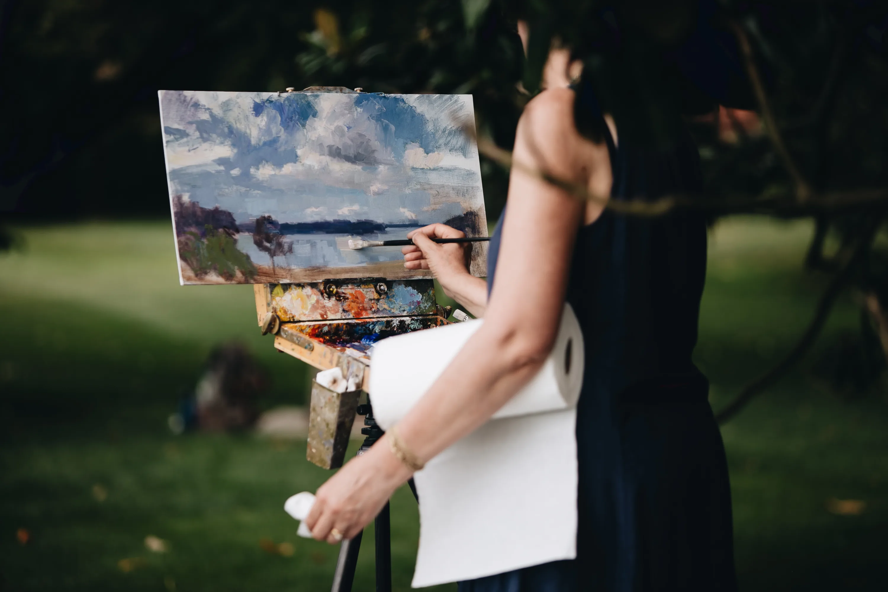 Woman painting a water view in plein air.