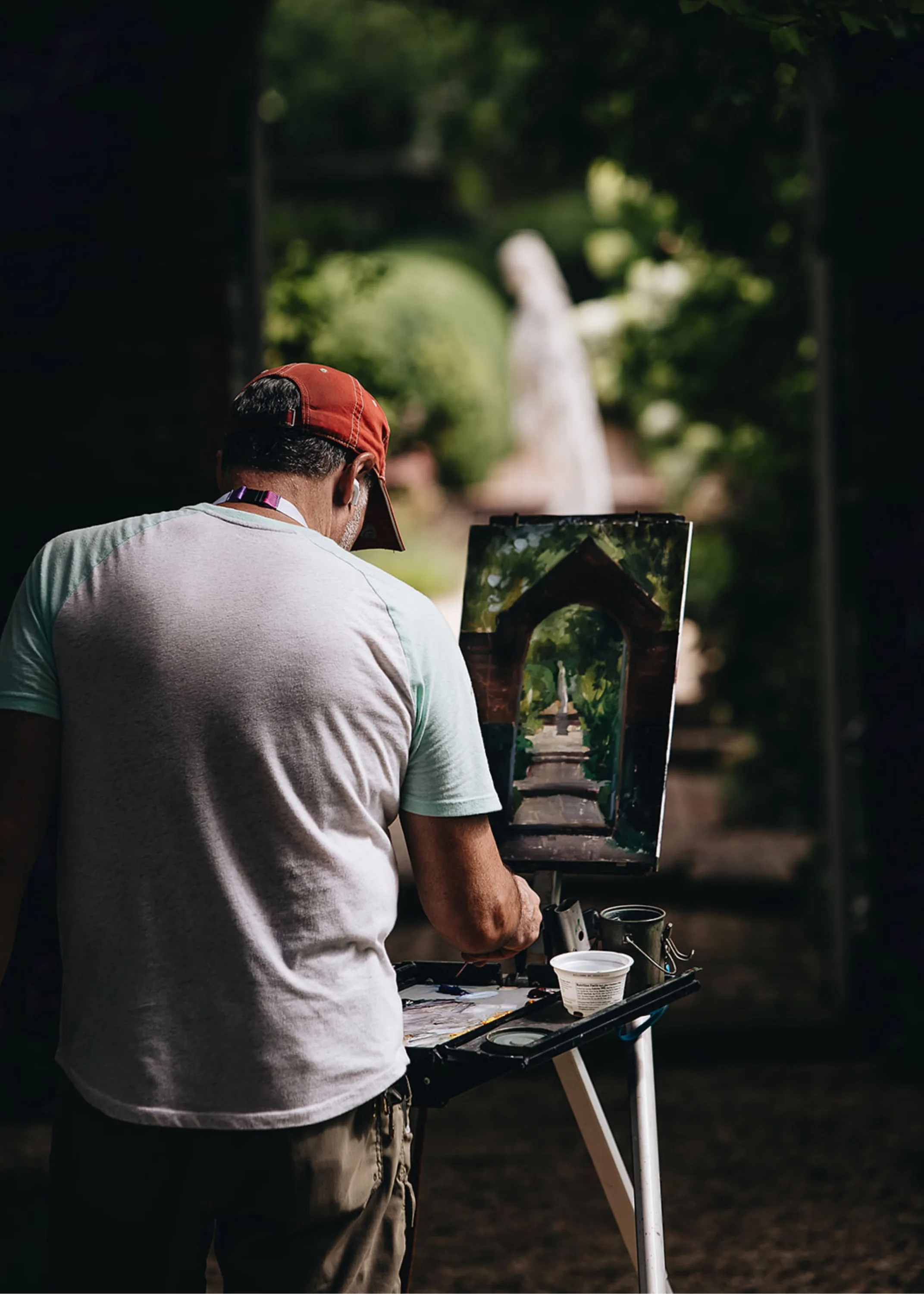 Man with his back to the camera painting in plein air.