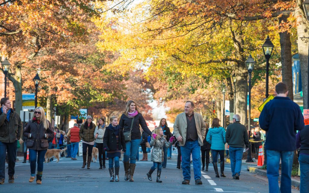 Family walking down street in Easton with fall foliage in the background during Waterfowl Festival.