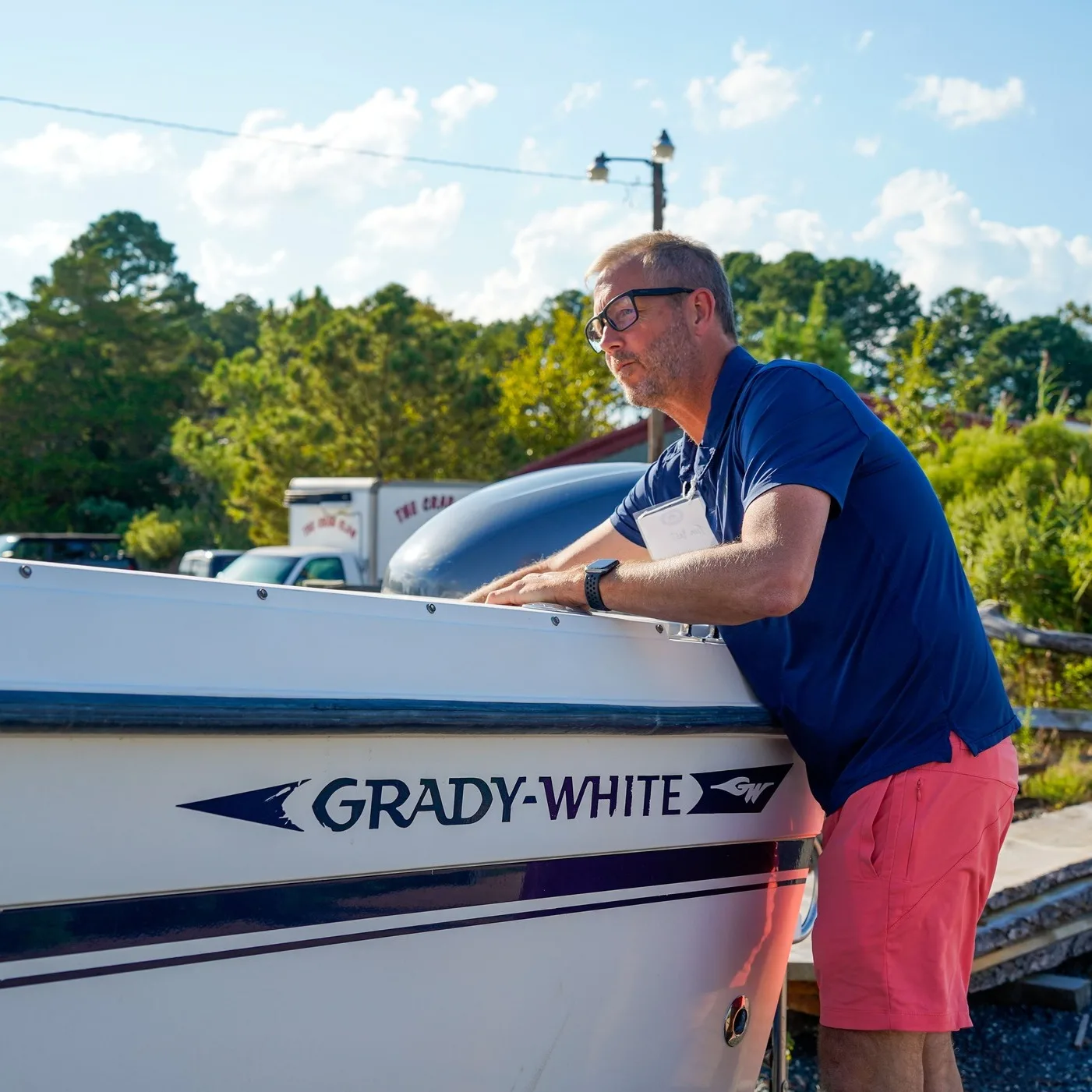 Man looking at a Grady-White boat. Standing to its side and leaning in to view or inspect it.