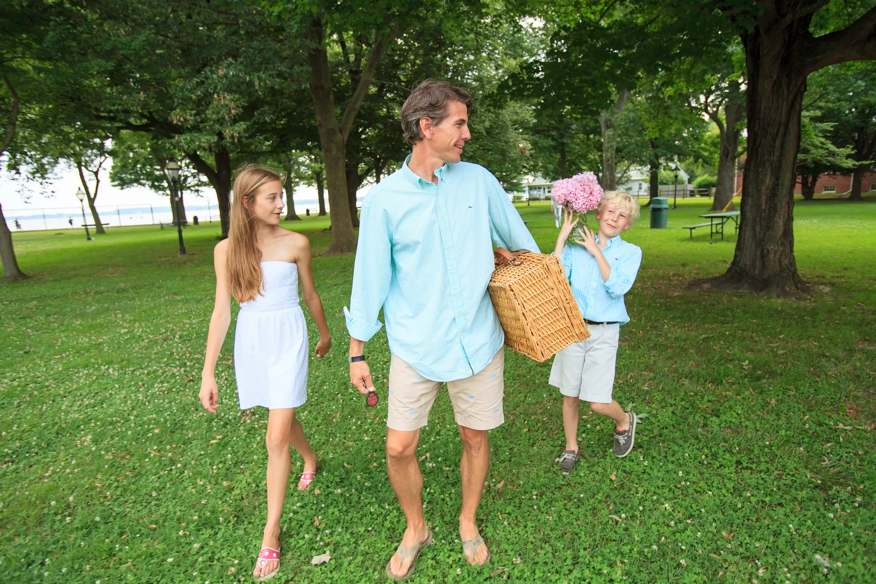 A father and children with picnic supplies for Mothers Day in the park.