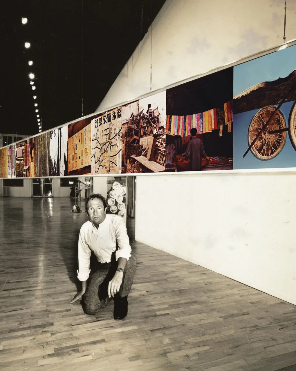 Man down on one new on a hardwood floor with colored artwork hanging above him on a banner.  