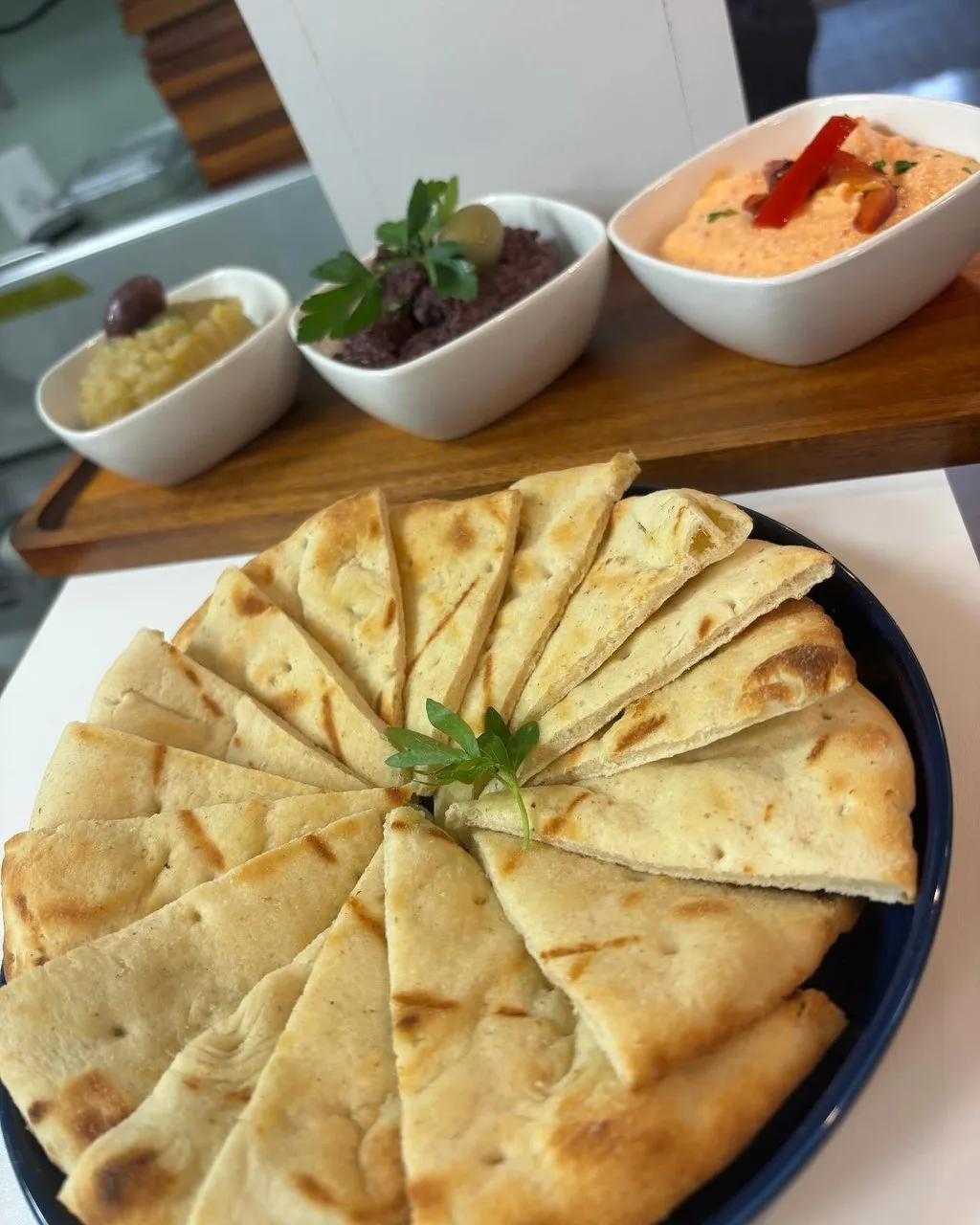 Food display, including pita or naan bread with a trio of hummus dips.
